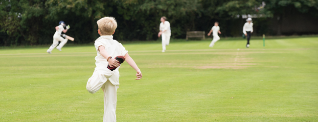 Cricket game in a Oxford Summer School A young boy is preparing for a cricket game on a sports field